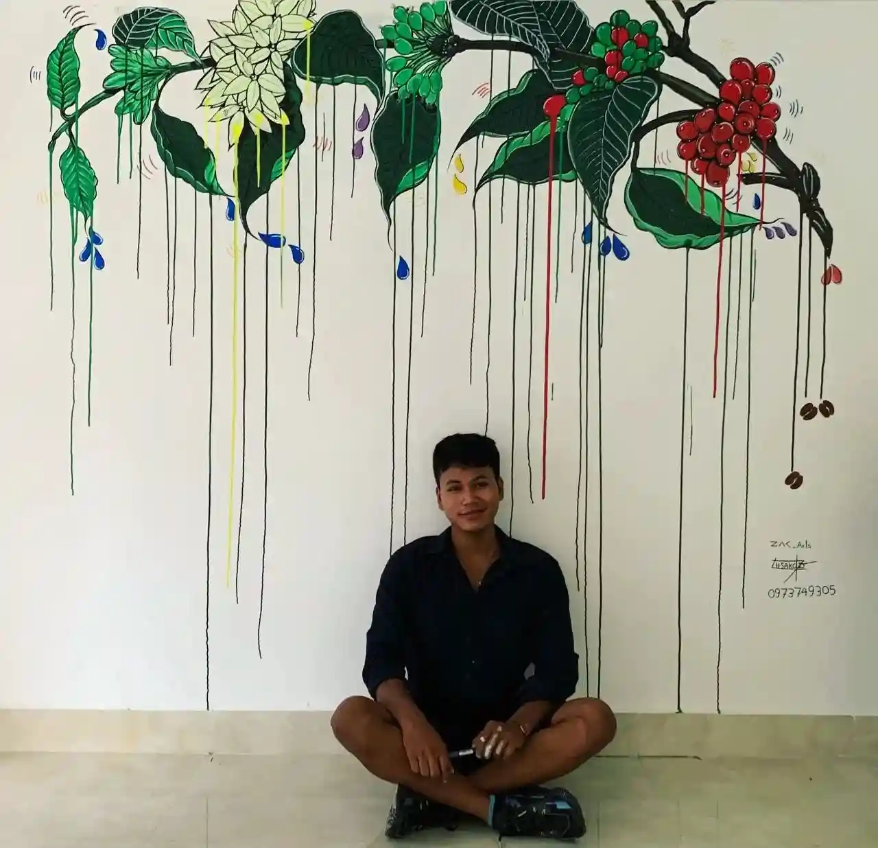 Cambodian artist Zak sitting in front of a colorful mural painting, contemporary Khmer art in Siem Reap