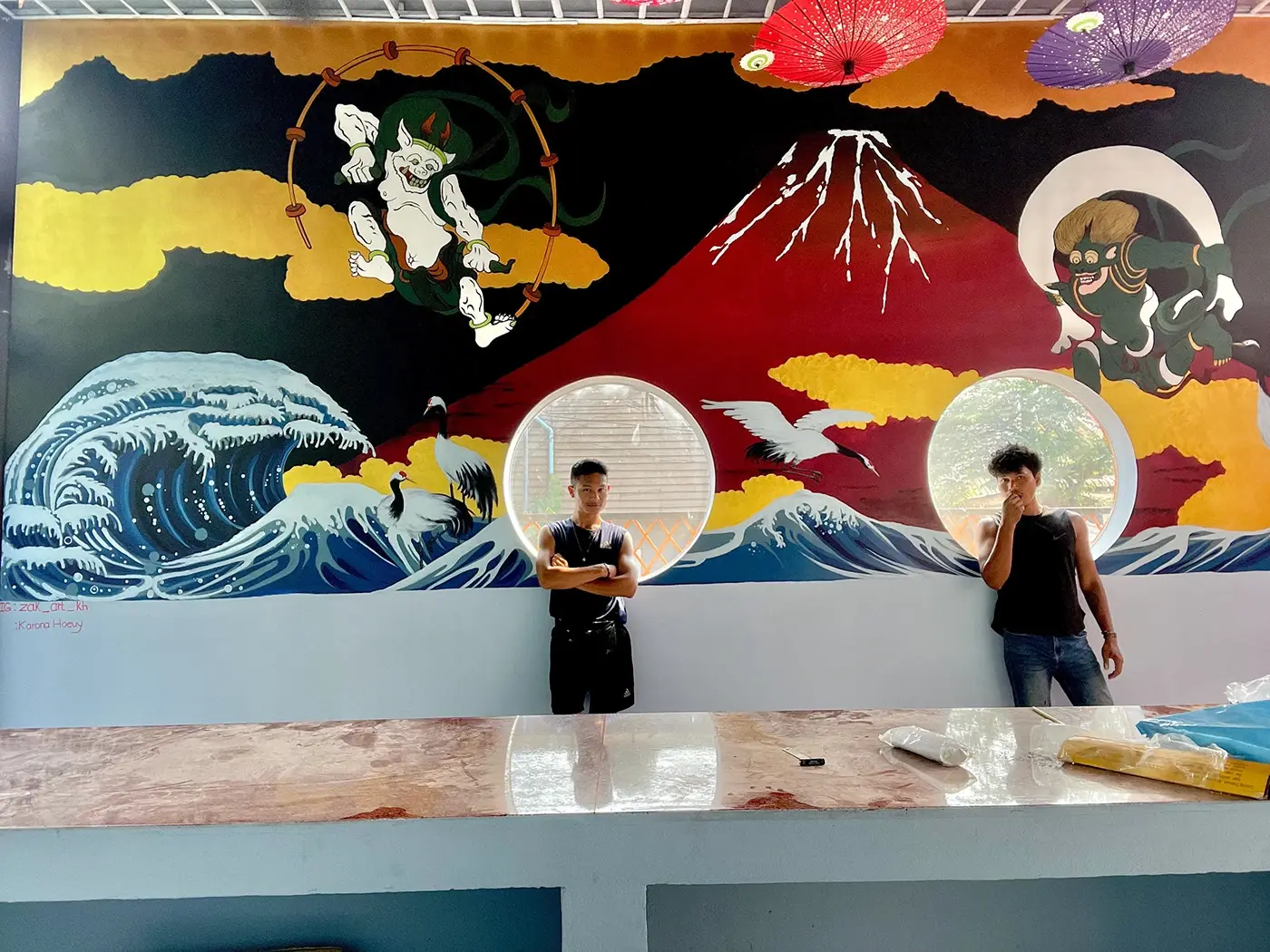 Cambodian artists Karona and Zak Arts in front of a large mural painting, contemporary Khmer art studio in Siem Reap
